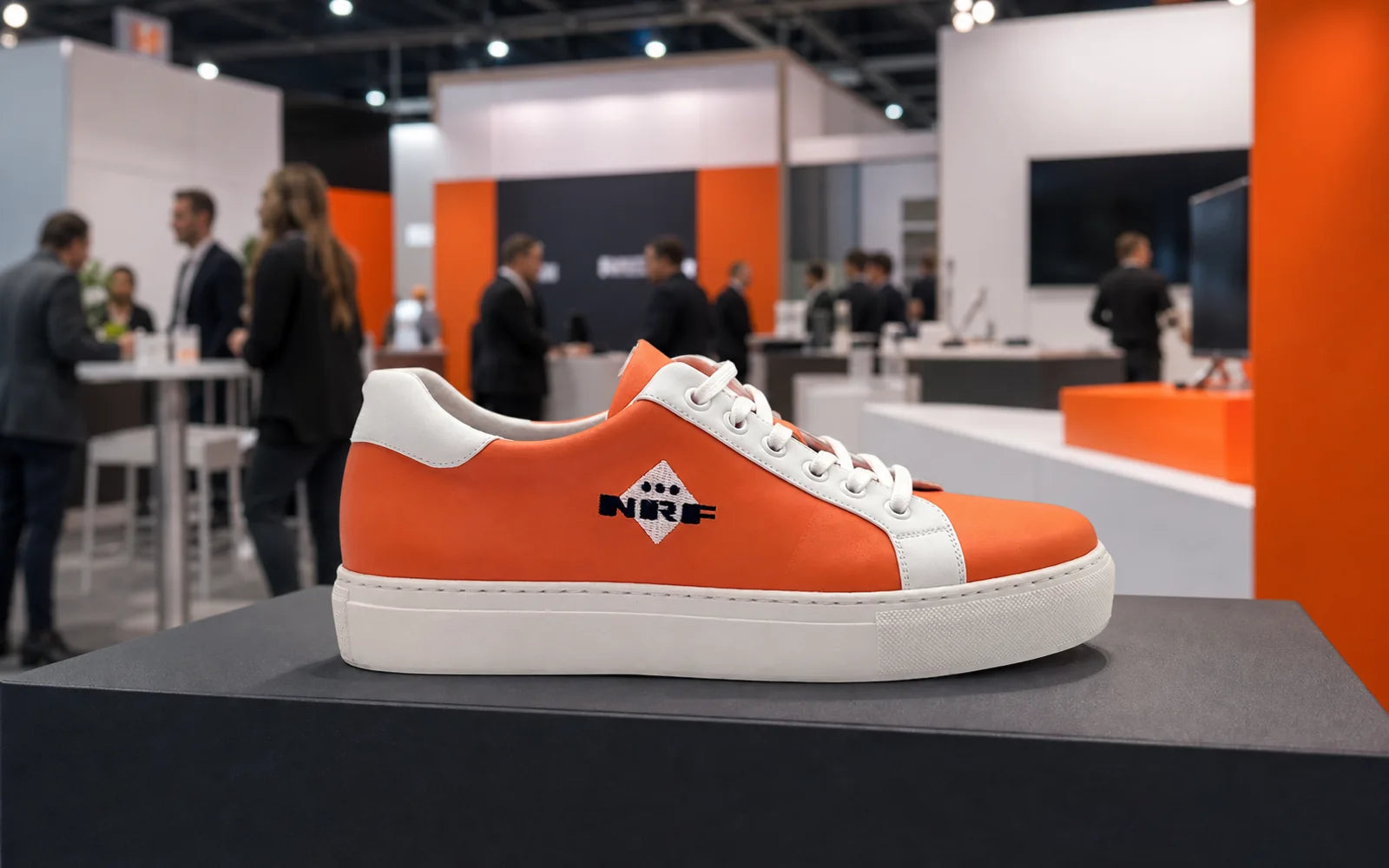 Custom branded orange sneaker displayed at a trade fair booth